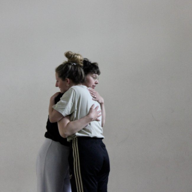 Die zwei Performerinnen Laura Kassé und Lisa Ennaoui umarmen sich.